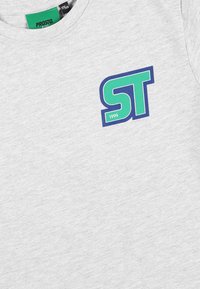 Szara bawełniana koszulka z krótkim rękawem, z niebieskim i zielonym logo "ST" oraz rokiem "1999" nadrukowanym z przodu.