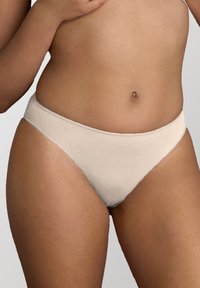 Perizoma in misto cotone beige con texture liscia, vita bassa e copertura minima, progettato per comfort e vestibilità.