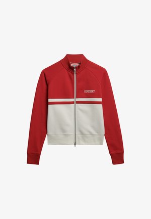 Chaqueta con cremallera roja y blanca con cuello alto, presenta rayas horizontales contrastantes y un pequeño logo en el pecho. Tejido suave y elástico.