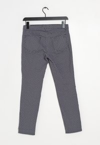 Navyblå leggings med ett vitt geometriskt mönster, tillverkade av stretchigt tyg, med en slät textur och standard midjeband, hängande på en krok.