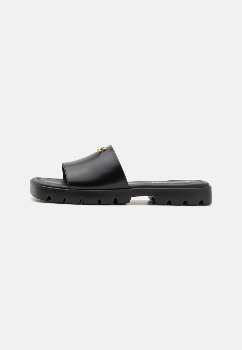 Mule negre cu un superior din piele netedă și mată și o talpă groasă din cauciuc texturat. Accente notabile din hardware auriu pe superior. Design simplu, deschis.