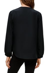 Schwarze Bluse mit langen Ärmeln und rundem Halsausschnitt. Das Design zeichnet sich durch geraffte Ärmel und einen leicht geschwungenen Saum aus, gefertigt aus glattem Stoff.