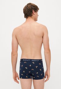 Navy patterned boxers with a birds motif; soft fabric, snug fit, and elastic waistband featuring the brand name "GANT."