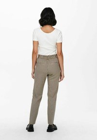 Rutig byxor i brunt och beige med resårmidja och slim fit. Matchas med en åtsittande vit t-shirt med kort ärm.