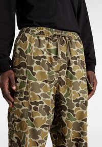 Camo cargobroek in tan, groen en bruin, met een elastische tailleband, trekkoordsluiting en zijzakken.