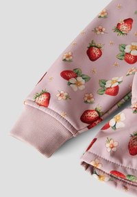 Tissu rose avec imprimé de fraises rouges et de fleurs blanches sur les manches avec poignets côtelés.