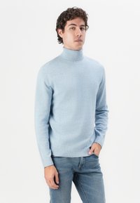Suéter de cuello alto azul claro hecho de suave tejido de punto, con mangas largas y dobladillo acanalado. Combinado con unos jeans de mezclilla casuales.