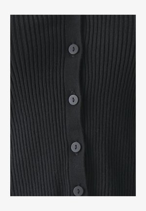 Černý žebrovaný cardigan s předním zapínáním na šest kulatých černých knoflíků. Textura je měkká a elastická, s vertikálním žebrováním.