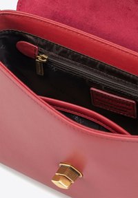 Rode leren handtas interieur met een ritsvak, gladde textuur en een gouden sluiting. Heeft een contrasterende donkere voering.