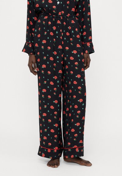 Ensemble de pyjama noir avec un motif floral de roses en rouge et vert. Pantalons à jambe large avec ceinture élastique et bordure rouge contrastante.