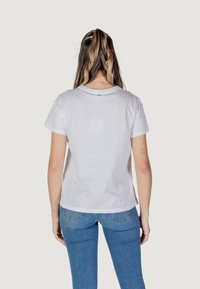 Camiseta blanca de algodón de manga corta y cuello redondo, con un corte relajado y detalles de costura mínimos en la parte trasera.