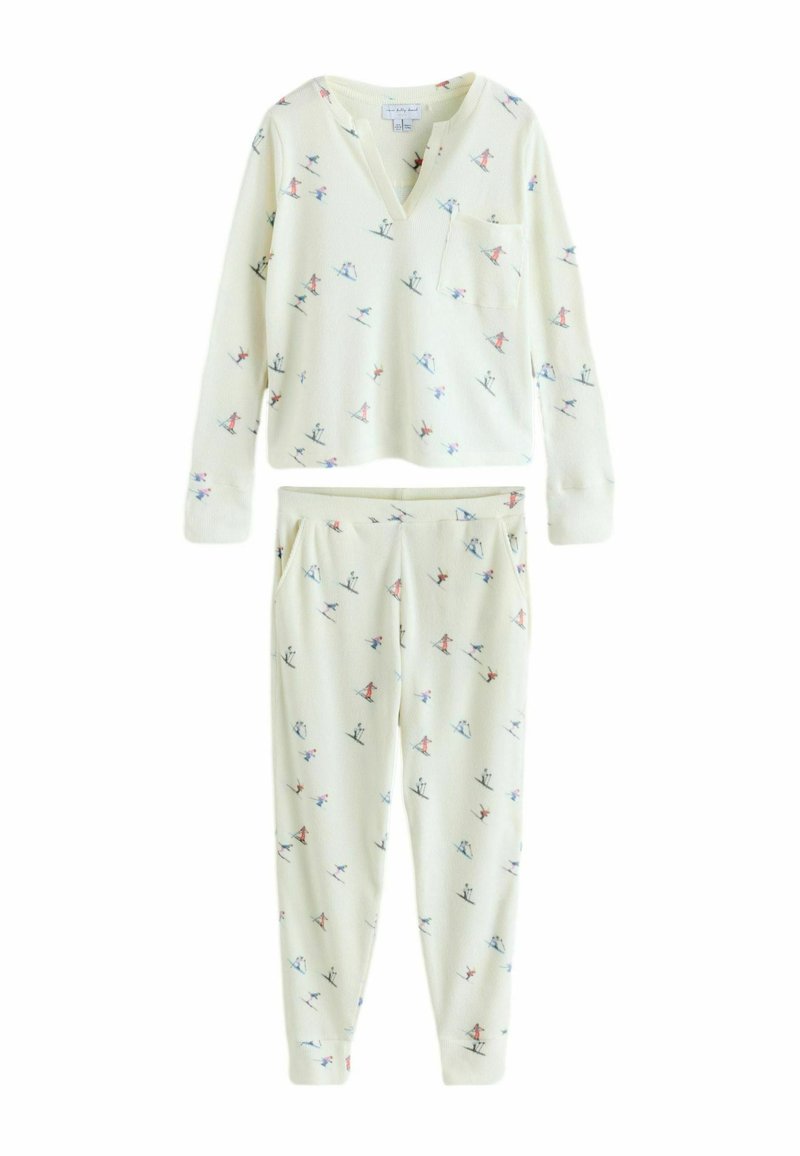 Hellcremfarbener Pyjama-Set aus weichem Stoff. Langärmliges Oberteil mit V-Ausschnitt und Brusttasche, kombiniert mit passenden Jogginghosen mit verspieltem Muster.
