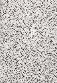 Tissu blanc avec un motif de points noirs dispersés. La texture semble lisse et légère, adaptée aux vêtements respirants.