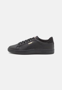 Black sneakers with a smooth leather upper, round toe, lace-up design, and gold Puma logo. Features a flat rubber sole and cushioned collar.