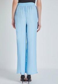 Pantalones de pierna ancha de color azul claro, hechos de tela suave con una cintura elástica, que presentan un corte relajado y un diseño fluido.