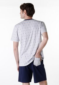 Maglietta grigia a maniche corte con una piccola stampa di ancore blu navy, abbinata a pantaloni corti blu navy. Il tessuto ha un aspetto testurizzato; la maglietta presenta un orlo arrotondato.