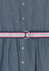 Abito camicia in denim con chiusura frontale a bottoni e gonna arricciata. Dotato di cintura a strisce multicolore con fibbia in metallo argentato.