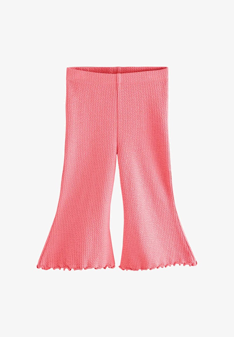 Różowe spódnice z rozszerzanymi nogawkami i charakterystycznym falbaniastym brzegiem. Tkanina ma wzór plasterka miodu, co tworzy głębię i wizualne zainteresowanie.