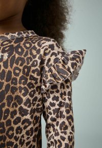 Braunes und beiges Leopardenmuster-Top mit gerippter Textur, ausgestattet mit Rüschendetails an den Schultern und einem runden Ausschnitt.