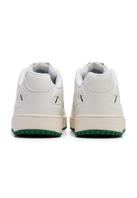 Vita lädersneakers med texturerad yta, med en beige sula och grönt accent på gummiyttersulan. Två sidoperforeringar nära hälen.