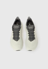 Αθλητικά παπούτσια ανοιχτού γκρι με άνω μέρος που αναπνέει, σκούρο γκρι κορδόνια και υφή λεπτομέρειες. Διαθέτουν θηλιά έλξης και ευλύγιστη σόλα.