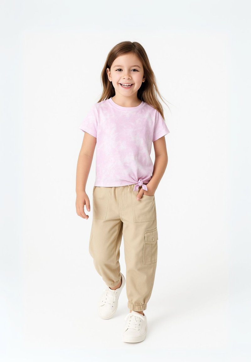 Lichtroze tie-dye t-shirt met korte mouwen, gecombineerd met beige cargobroek met zijzakken en elastische boorden, gedragen met witte sneakers.