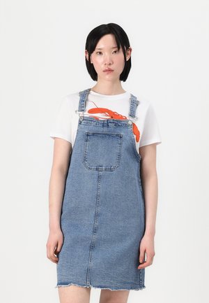 Denim overallkjole, lyseblå, mid thigh-lengde, fremre lomme, frynset kant, brukt over en hvit t-skjorte med et oransje hummer-graphic.