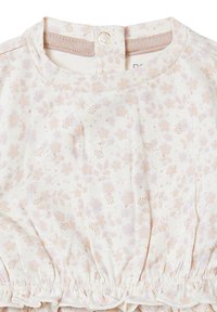 Haut à motif floral en tissu crème doux, orné de fleurs pastel en rose et lilas, avec une taille froncée et une fermeture pressionnée au dos.