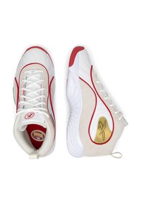 Valged ja beežid sportlikud jalanõud punaste aktsentidega ja kuldse logoga, kujutatud pealt ja küljelt valgel taustal.