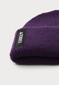 Berretto in maglia viola realizzato in lana testurizzata, con risvolto e un'etichetta nera con dettagli di branding bianchi.