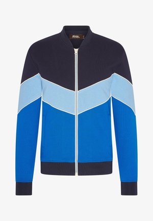 Blauwe bomberjack met blokken in marineblauw, lichtblauw en luchtblauw. Voorzien van een ritssluiting, geribbelde manchetten en zijzakken.
