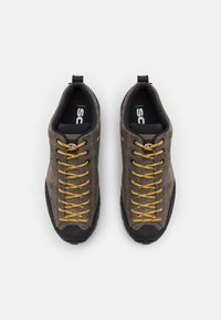 Pantofi din suede gri cu talpă din cauciuc negru, cu șireturi galbene, vârf întărit și guler căptușit pentru un plus de confort.