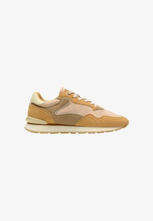Beige en tan suède sneaker met een crèmewitte zool en veters, lage schoen met een strak, gelaagd paneelontwerp aan de zijkant.