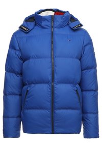 Blauwe pufferjas met hoge kraag, ritssluiting aan de voorkant en twee zijzakken. Is voorzien van zwart-witte schouderaccenten en logo-detail.