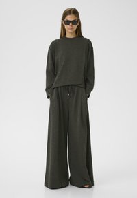 Set di abbigliamento casual a due pezzi grigio scuro, composto da una maglia a maniche lunghe dal fit rilassato e pantaloni a gamba larga con vita regolabile. Tessuto morbido.