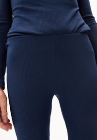 Top de manga larga acanalado en color marino, combinado con leggings acanalados a juego. El material parece elástico, con un diseño ajustado y cintura sin costuras.