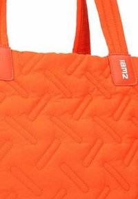 Borsa a tracolla imbottita arancione con un motivo geometrico, texture morbida, manici resistenti e un piccolo etichetta con il marchio nell'angolo.