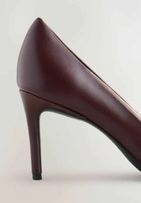 Bordeaux hoge hak schoen met een puntige neus, een gladde lederen buitenkant en een slanke hak met een zwart accent aan de basis.