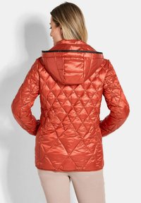 Rote gesteppte Steppjacke mit Kapuze, glänzendem Finish, diagonalem Steppmuster und schwarzen Akzenten am Halsausschnitt.