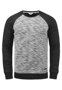Sudadera de cuello redondo en gris y negro con mangas raglán. Textura suave, cuerpo estampado, puños y dobladillo negros con una pequeña etiqueta de la marca en el lado inferior.