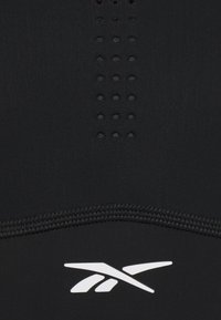 Top de desporto preto sem mangas com painéis texturizados e orifícios para ventilação, apresentando um logo branco na parte inferior e detalhes costurados.