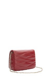 Borsa a tracolla in pelle trapuntata rossa con tracolla in catena dorata e cuciture a motivo ondulato su sfondo bianco.