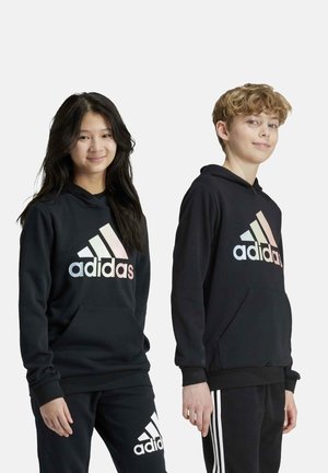 Felpa nera con cappuccio e logo "adidas" sfumato. Presenta una tasca frontale e polsini a costine. Abbinata a pantaloni neri coordinati.