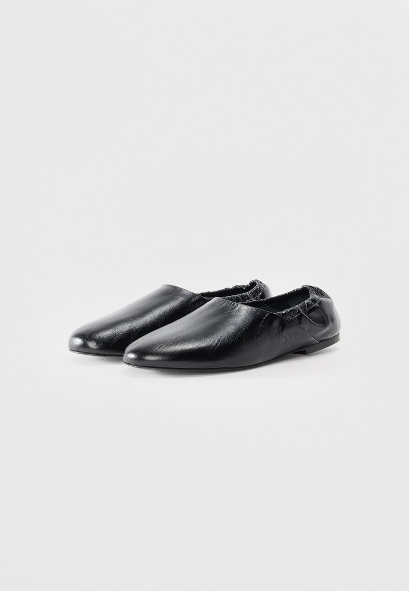 Black leather shoes with a sleek, pointed design and elasticized edges for a snug fit. Smooth texture with minimal detailing.