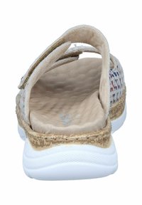 Sandale beige avec une tige texturée et une sangle réglable. Semelle intérieure rembourrée et semelle blanche avec une base marron à motifs.