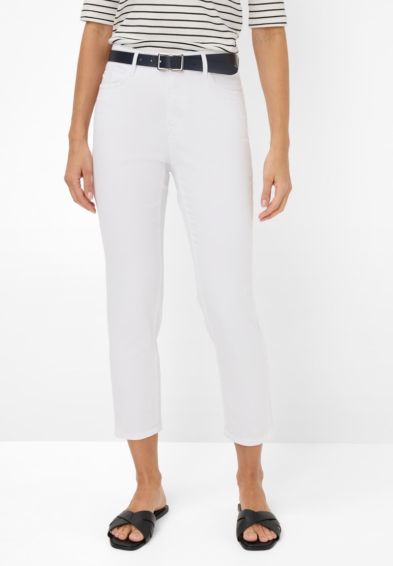 Weiße, kurze Jeans mit glatter Textur, ergänzt durch einen navyblauen Gürtel, getragen mit schwarzen Riemensandalen. Ein horizontal gestreiftes Oberteil sorgt für einen Kontrast.