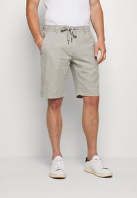Light grey linen shorts with an elastic drawstring waistband and side pockets, worn with a white T-shirt and white sneakers.