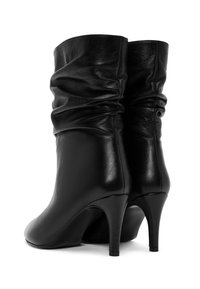 Czarne skórzane botki za kostkę o luźnym fasonie, z wysokimi obcasami w stylu stiletto i gładką fakturą, z delikatnym marszczeniem u góry.