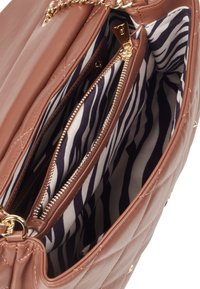 Borsa a tracolla in pelle marrone trapuntata con hardware dorato; l'interno presenta una fodera a righe navy e bianche e scomparti con zip per l'organizzazione.