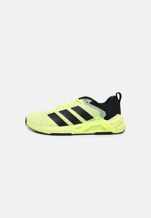 Chaussure de sport vert clair et noire avec trois bandes noires sur le côté et une boucle de talon de maintien sur un fond blanc uni.